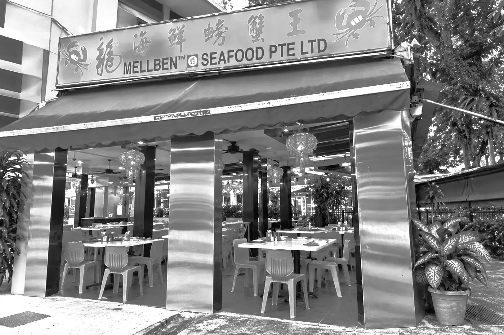 Exterior of Mellben Seafood restaurant featuring its large Chinese and English signage, striped awning, open dining area, and surrounding greenery.