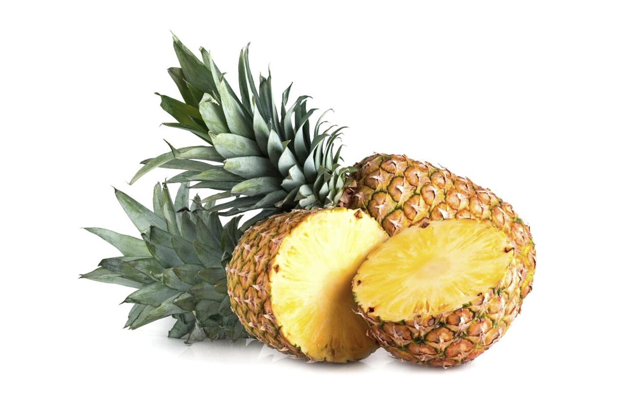 An image of a whole pineapple beside one cut in half on a white background.