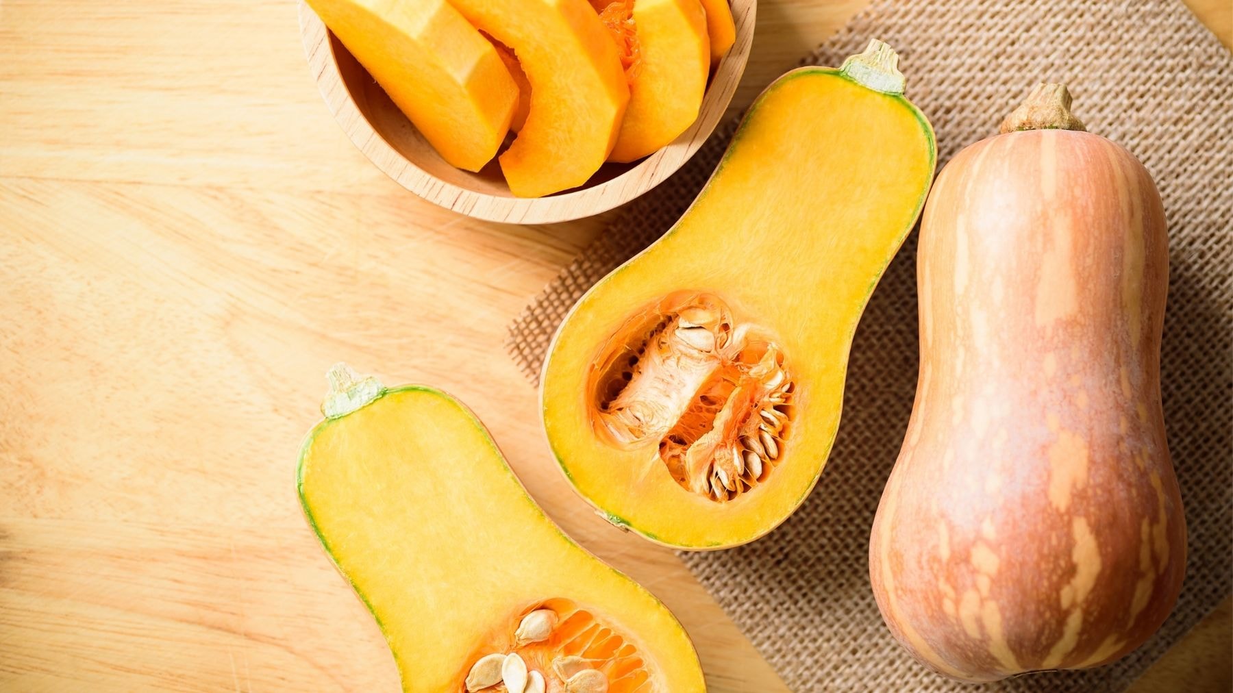 Whole and sliced butternut squash on a wooden surface