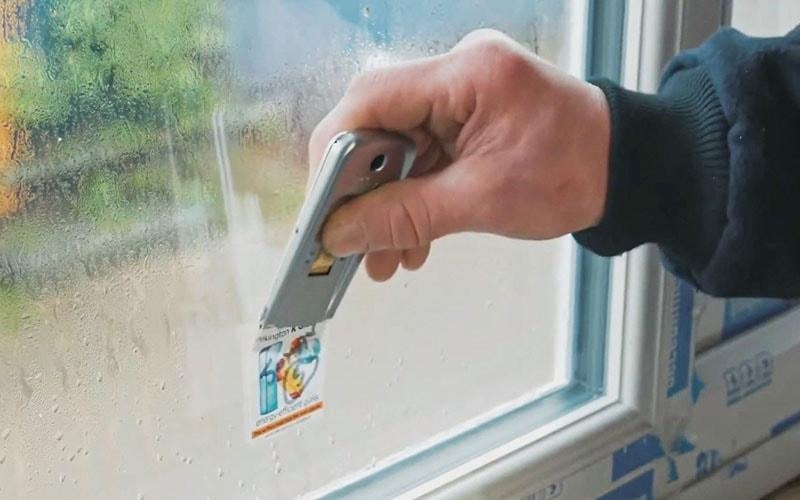 Removing sticker from glass using metal scrapper