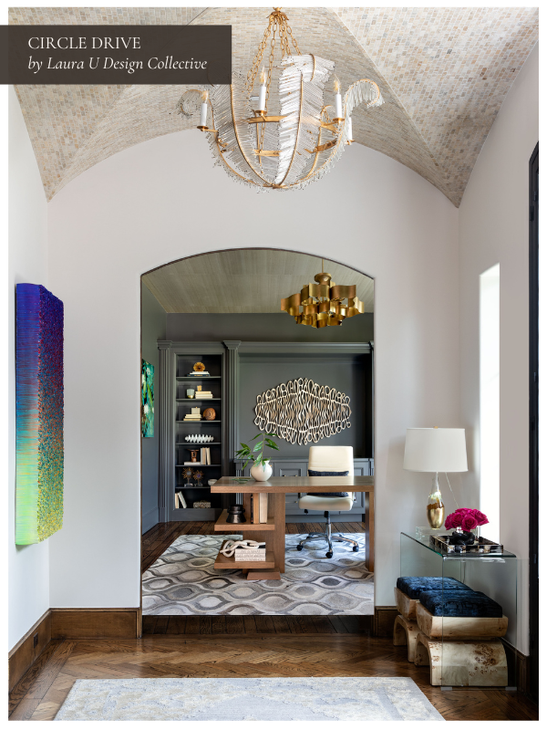 A vaulted entryway with a mosaic-tiled ceiling and chandelier opens into a home office framed by an arched doorway. A vibrant gradient artwork hangs on the left wall, while warm wood floors and layered lighting create a refined, welcoming atmosphere.