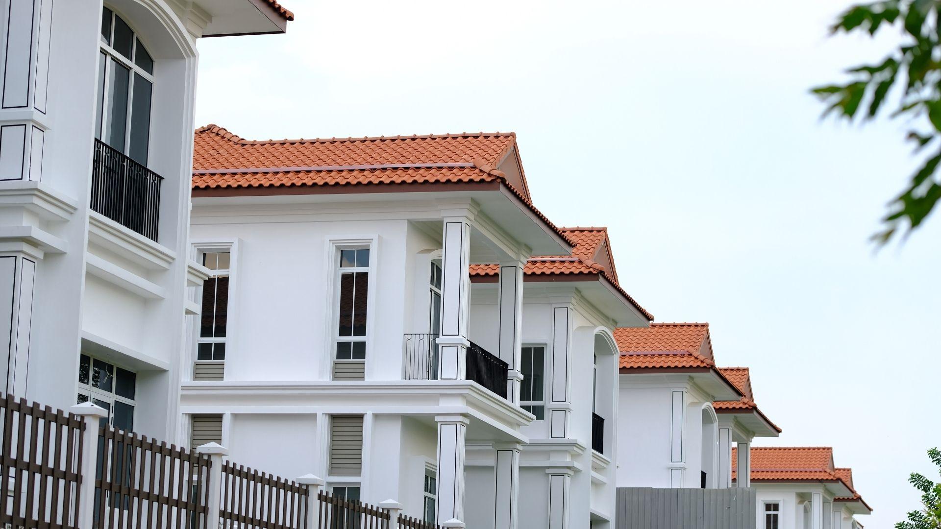 Row of modern white residential houses with terracotta roofs in a suburban neighbourhood.