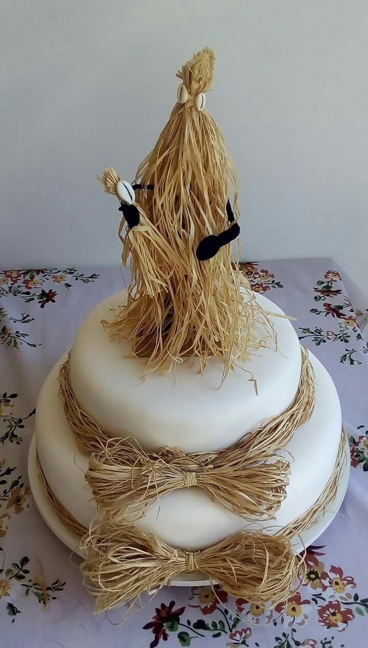 A two layered cake tied with straw decoration with a straw-inspired masquerade at the top