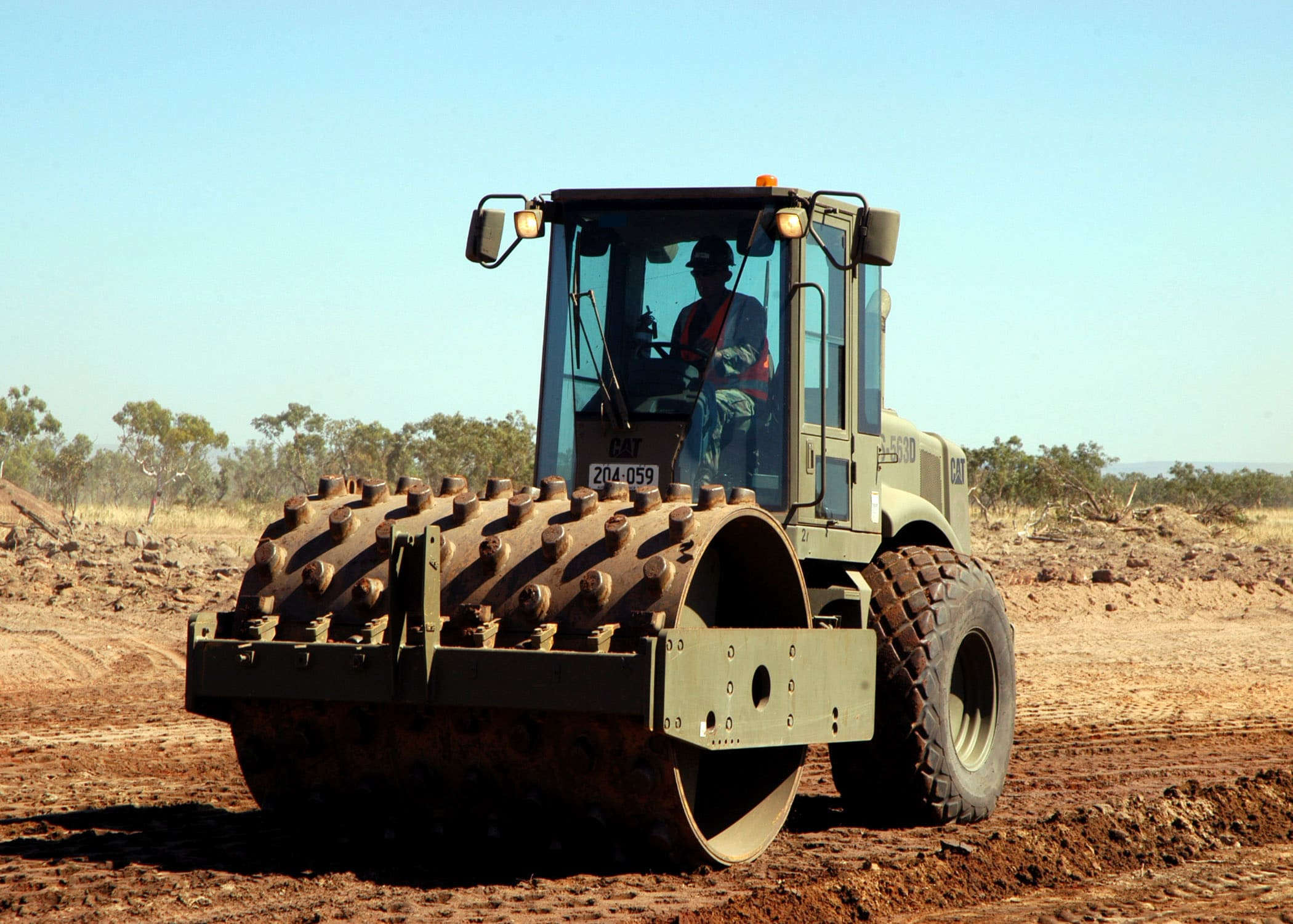 Heavy machinery with a large roller used to compress soil, gravel, or asphalt during construction projects
