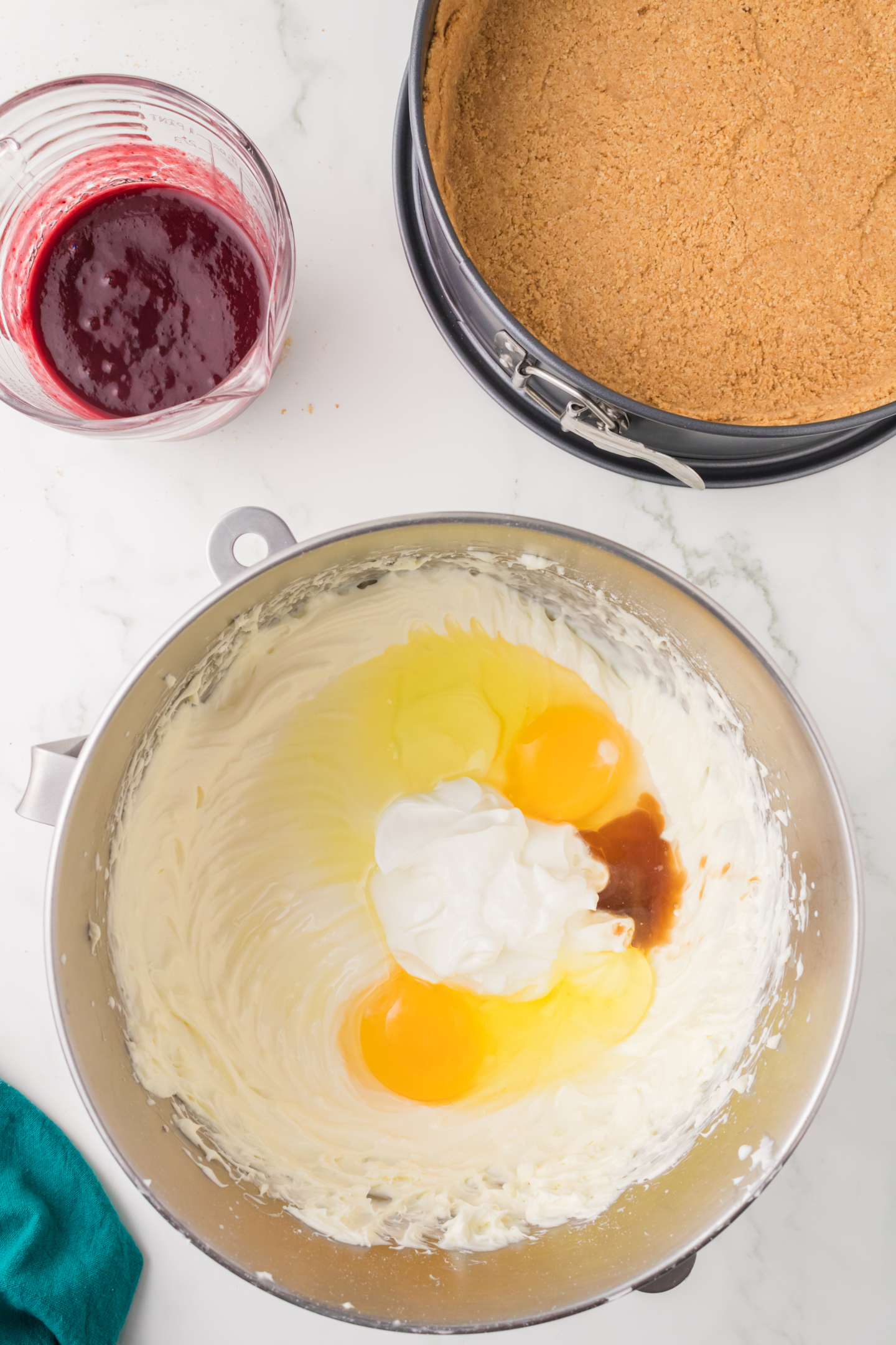 eggs, sour cream, and vanilla extract added to bowl of cheesecake mixture