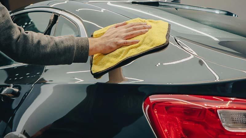 Lint-free car cleaning with a yellow microfiber towel