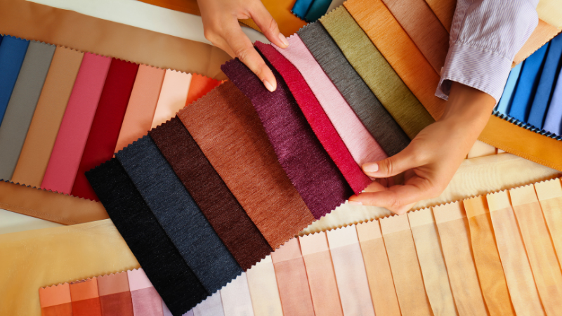 A person is holding a sample of different colors of cupro fabric.