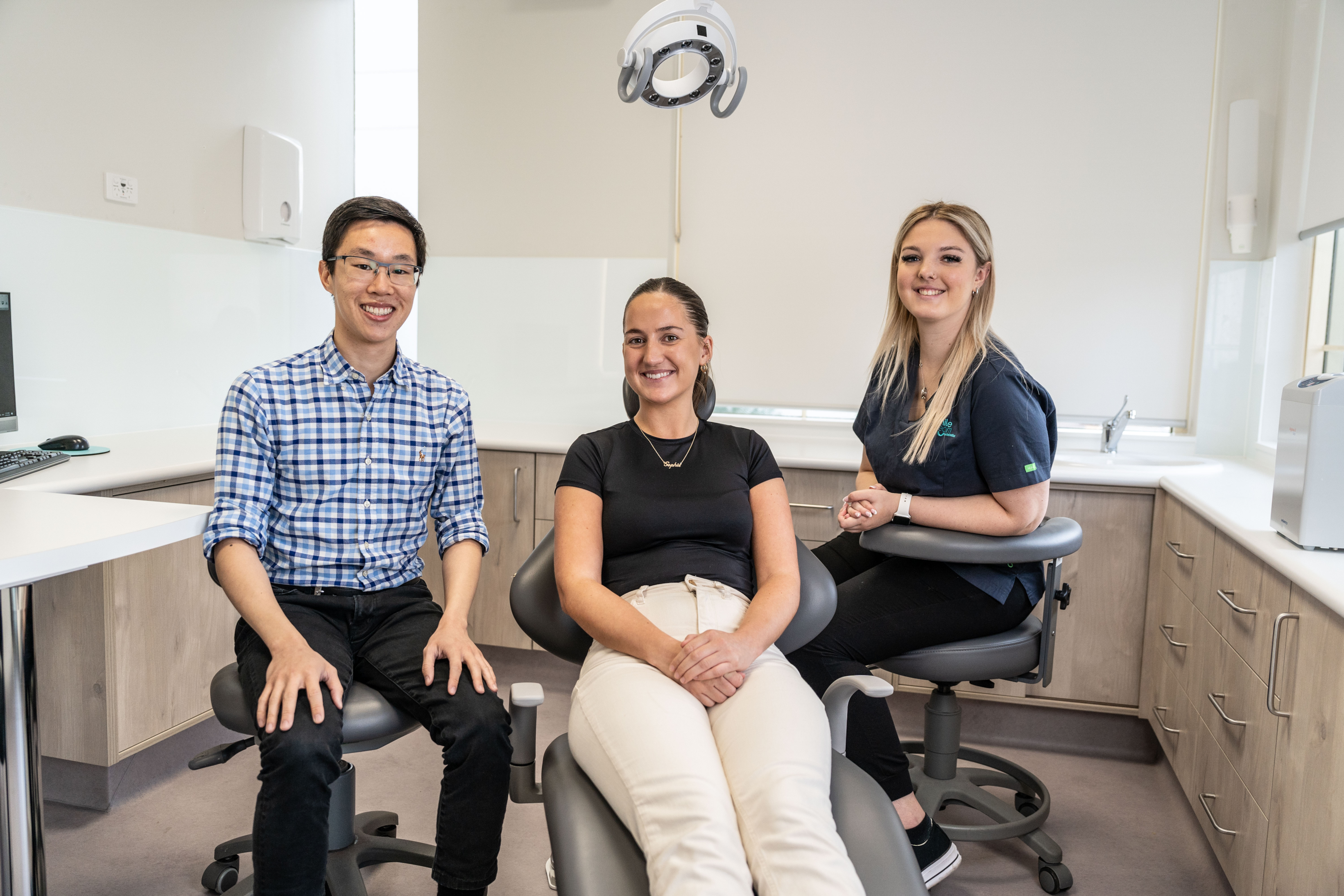 Cheerful young woman having dental examination in clinic with an orthodontist and nurse