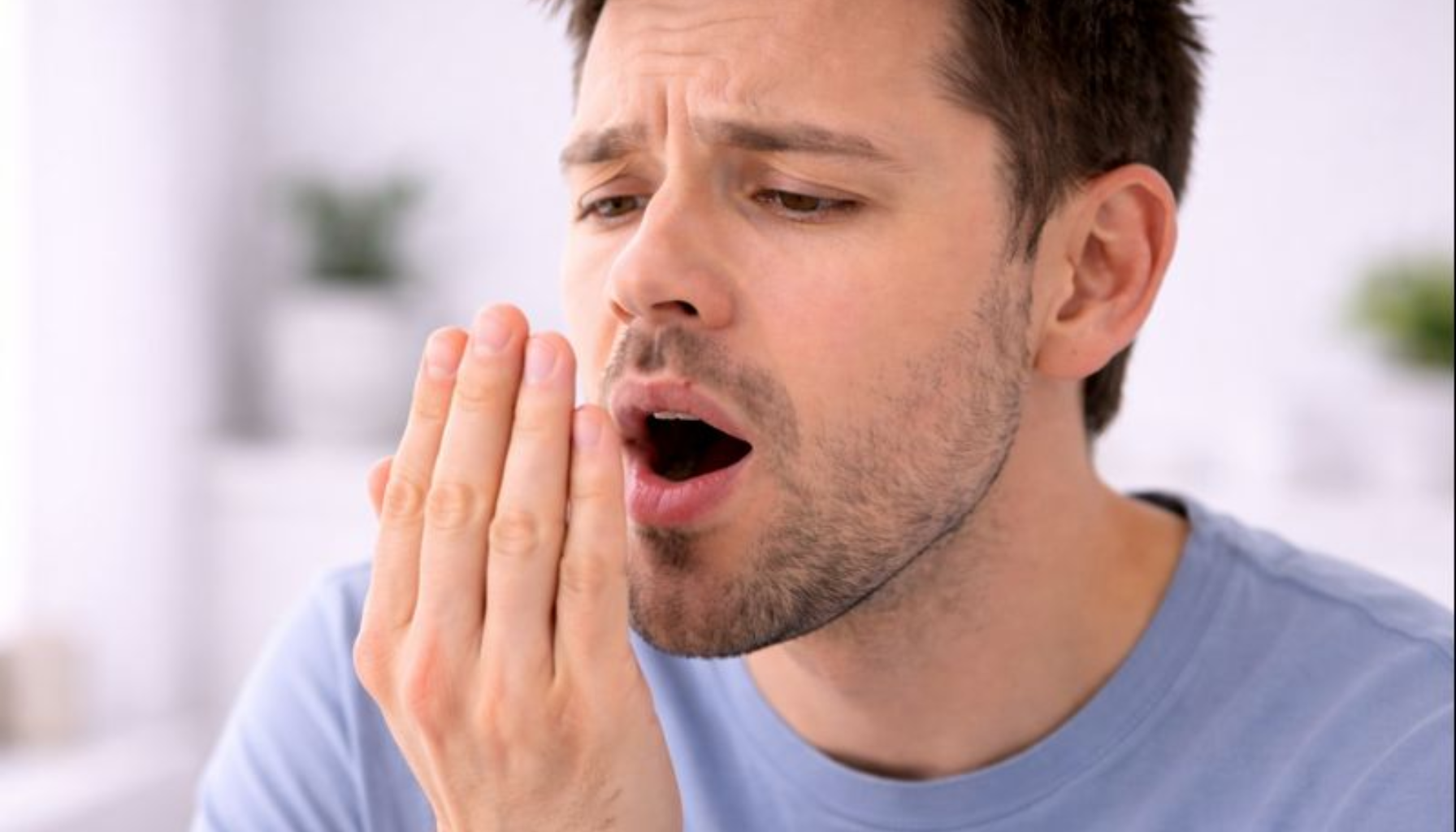 Aceton Ånde: Hva Den Spesielle Lukten Kan Betyr 12 En mann holder hånden foran munnen, uttrykker ubehag og mulig dårlig ånde i naturlig belysning.