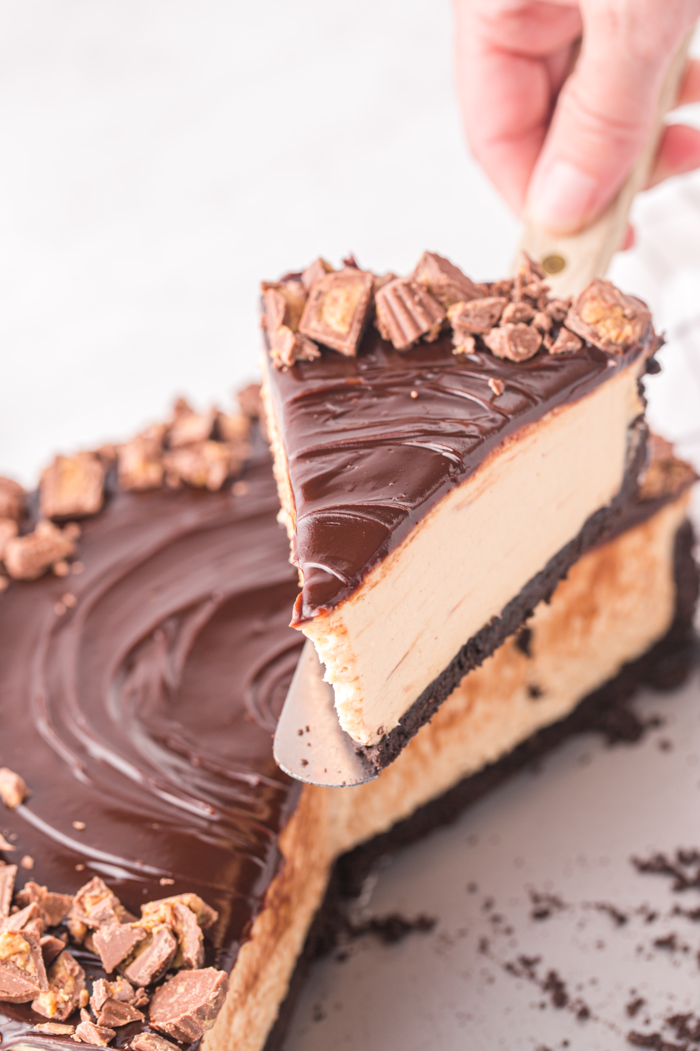 hand serving a slice of no bake peanut butter cheesecake