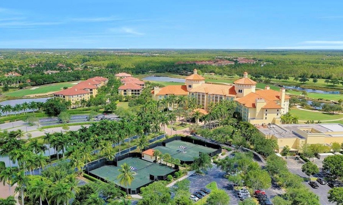 The image depicts a luxurious condominium building surrounded by lush landscaping and featuring a resort-style pool and spa oasis, embodying the essence of resort-style living. This refined residence offers an inviting atmosphere with expansive outdoor spaces, perfect for enjoying the exceptional private retreat that is characteristic of the Tibur&oacute;n Naples community.