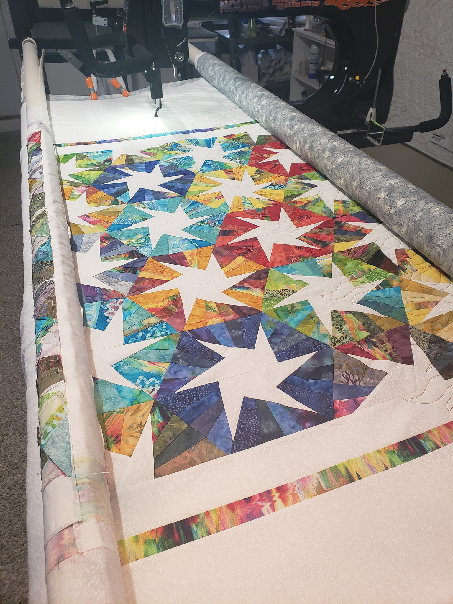 Image shows Debby's Scrappy Whirligig project on her longarm using one of our quilt patterns