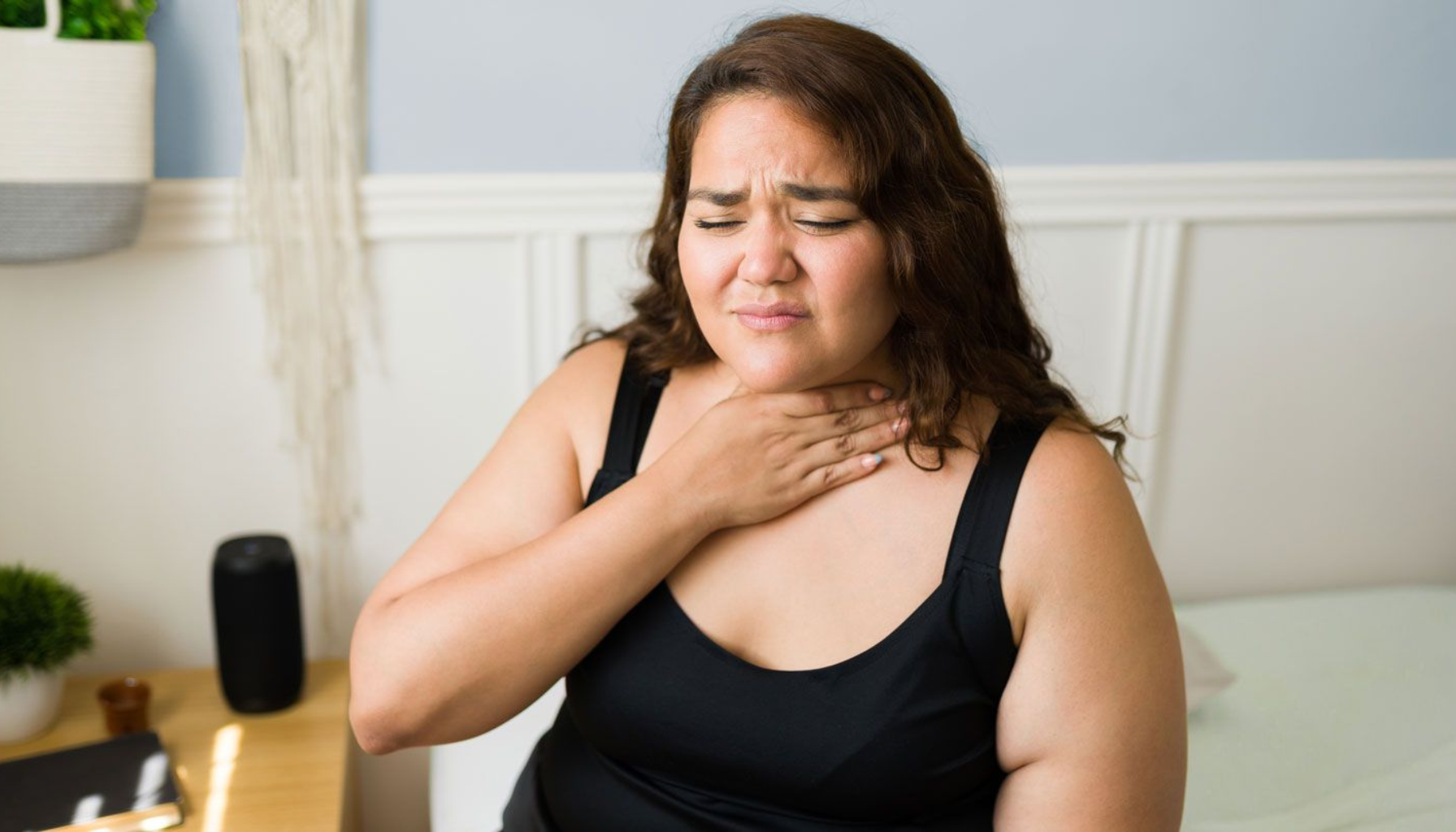 Kvinne holder seg på halsen – sår hals under sykdom.