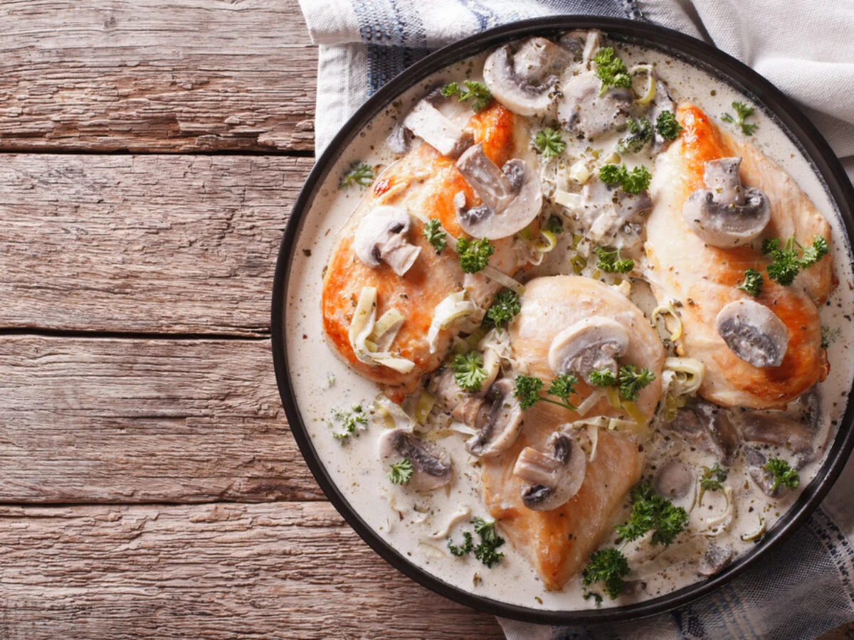 A bowl of keto chicken soup cooked in a slow cooker with raw chicken, net carbs, and skinless chicken thighs