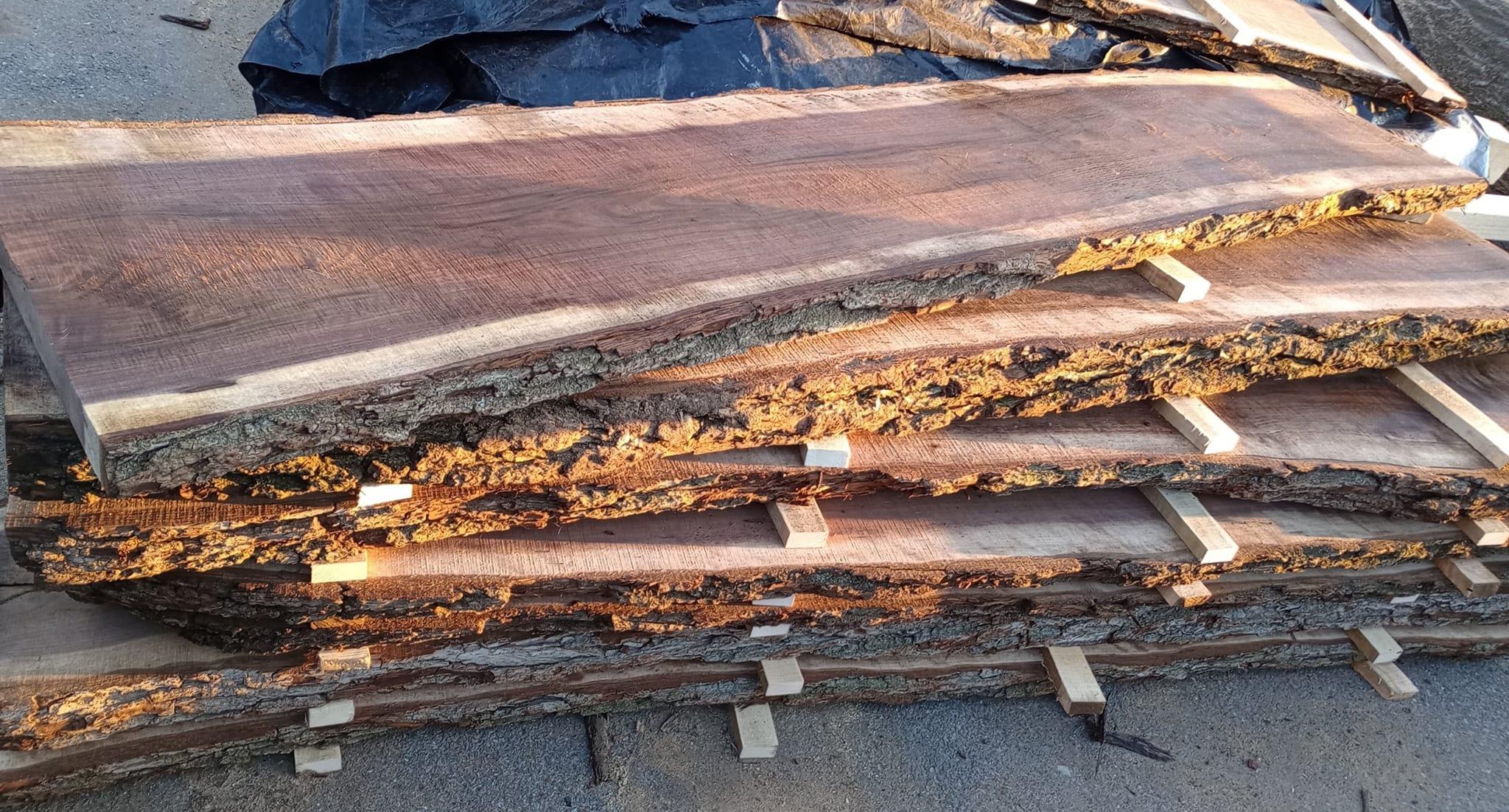 Une pile de planches à bords naturels, avec des autocollants entre les planches.
