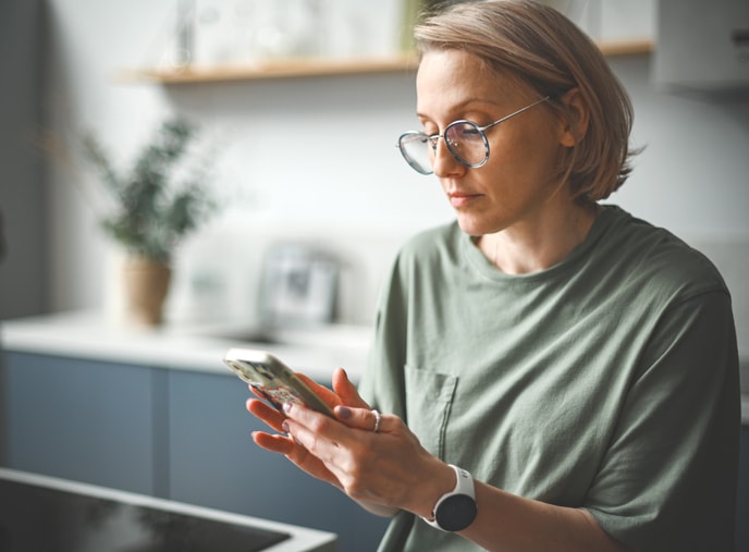 Blonde woman in glasses looking at her cell.