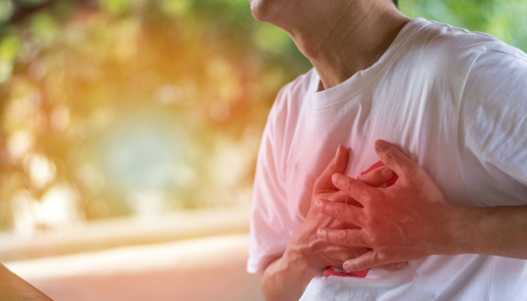 Person holder seg til brystet i smerte, muligens på grunn av hjerteproblemer eller kraftig ubehag i brystet.