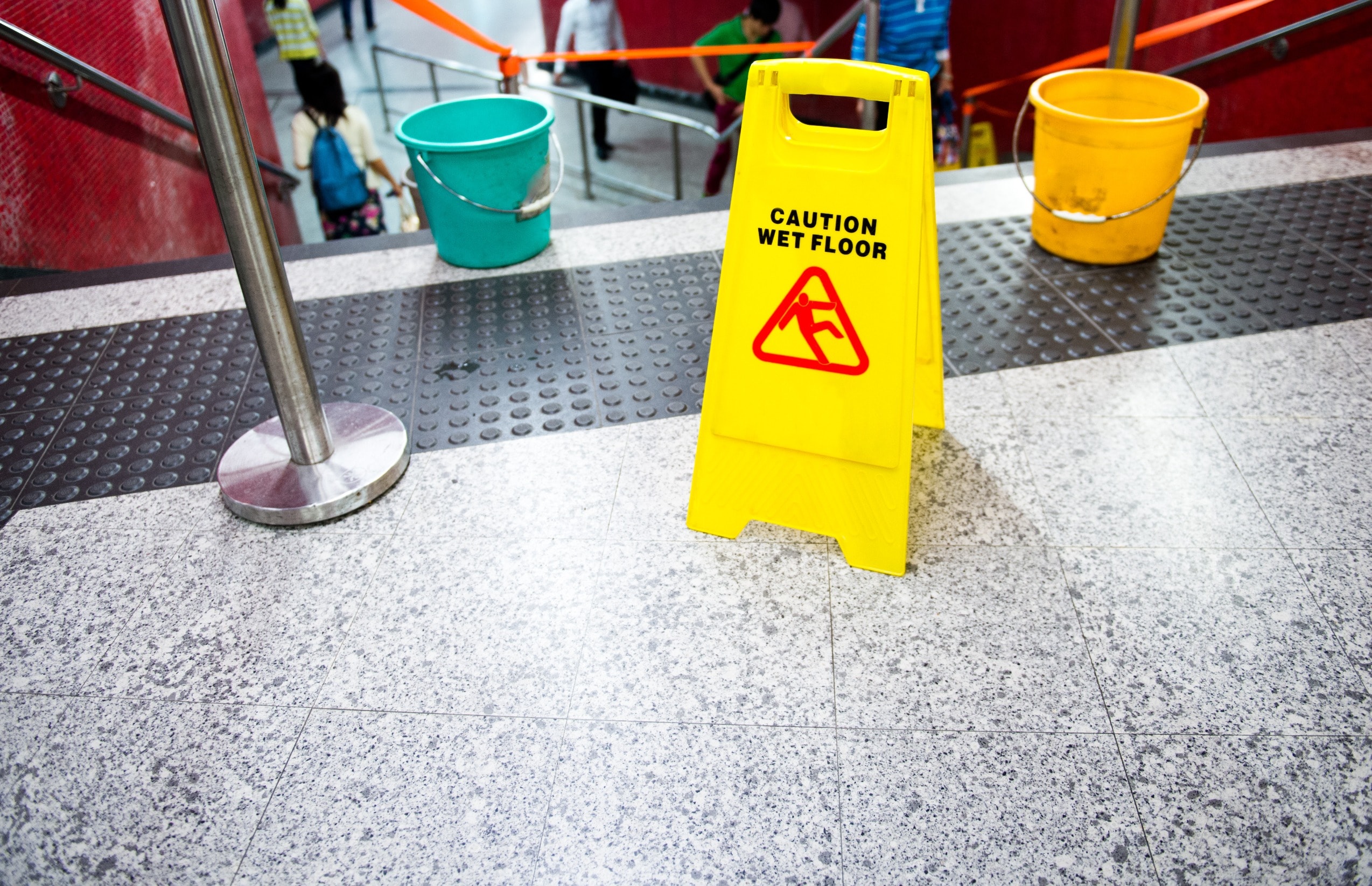 A wet floor sign at the top of a set of stairs