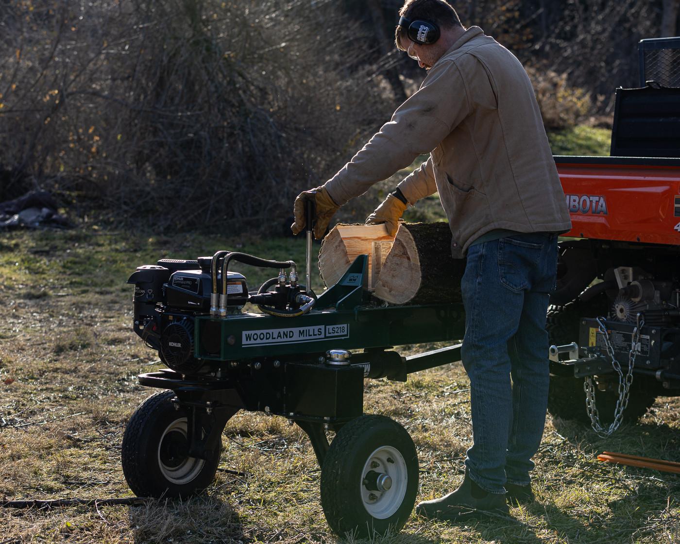A man operating a Woodland Mills LS218 2-Way Log Splitter to cut a log in half.
