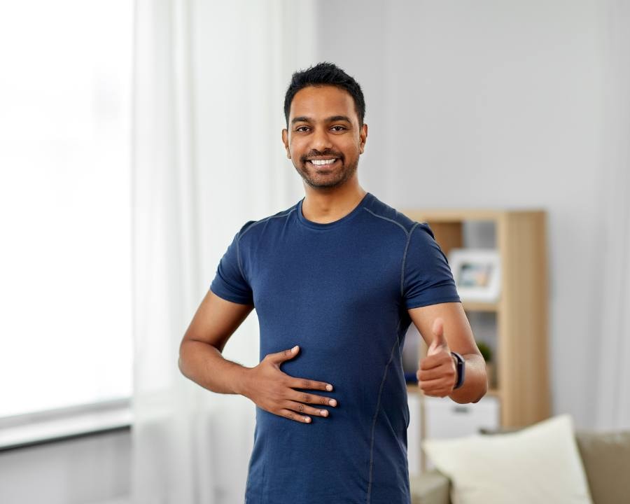 Indian man smiling and holding his healthy gut