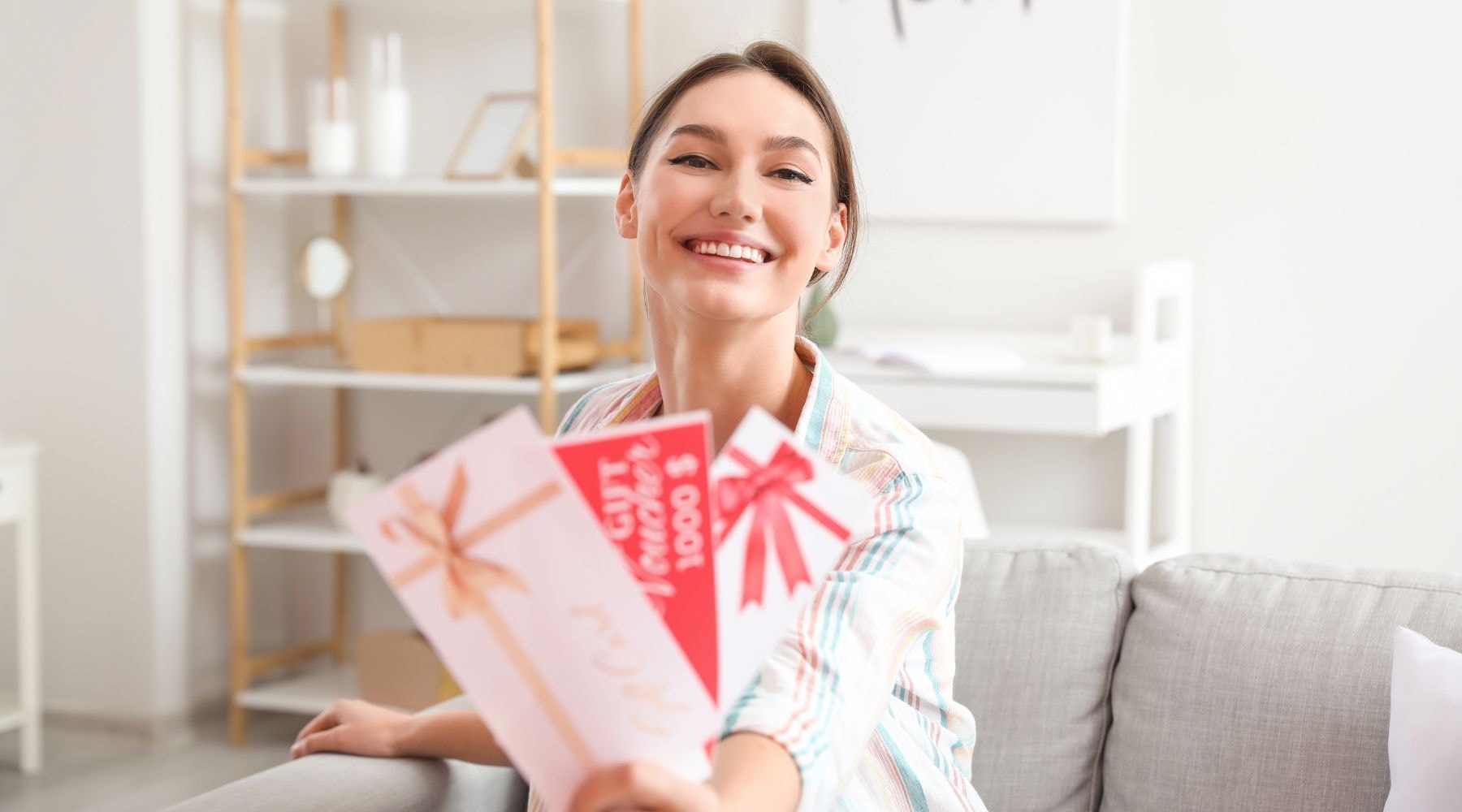 Smiling woman showing gift vouchers in a modern living room.