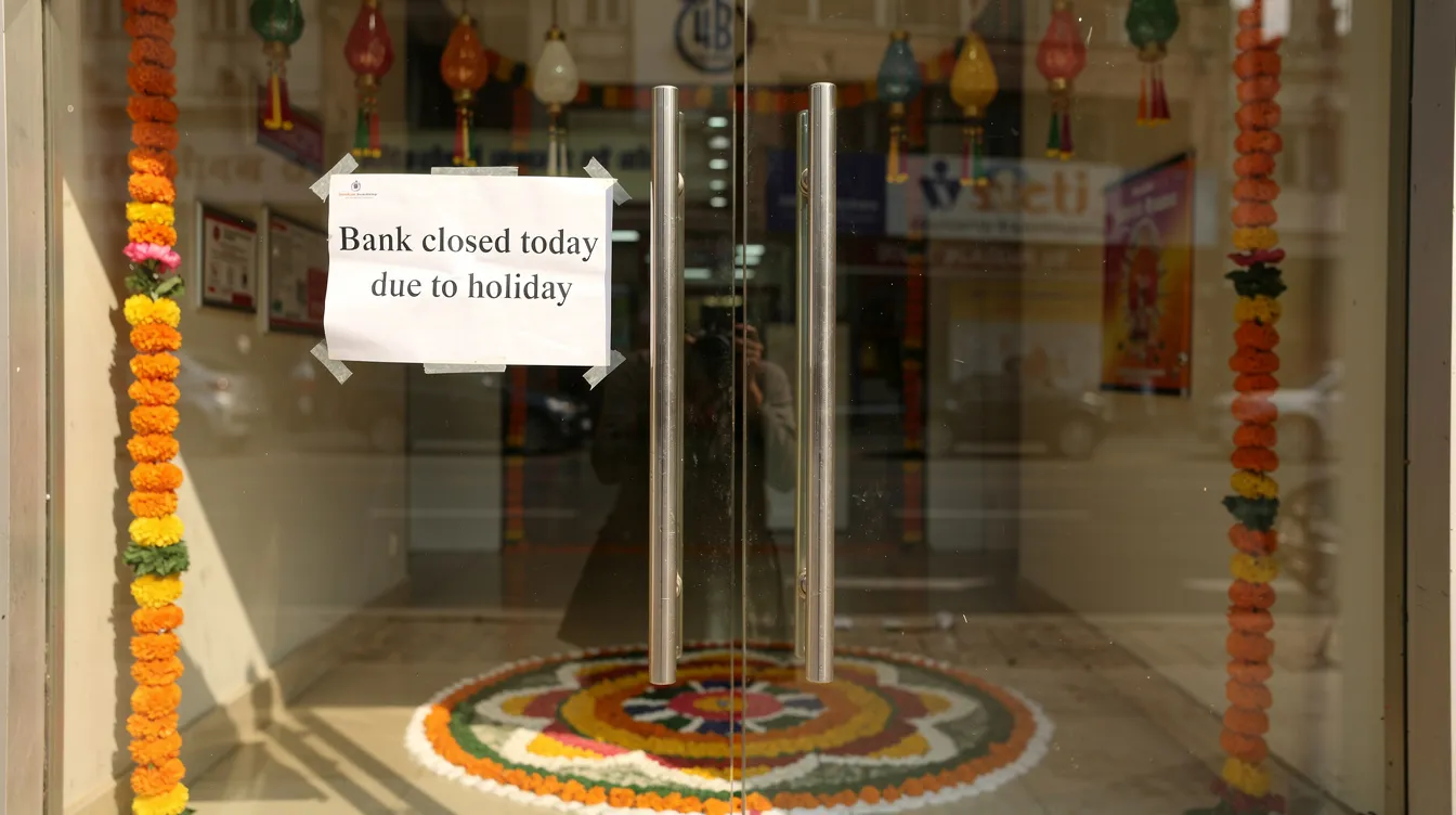 The image shows a closed bank branch door adorned with a holiday notice sign, while traditional Indian festival decorations are visible in the background, creating a festive atmosphere. This scene highlights the impact of holiday seasons on financial institutions, particularly for those seeking assistance with schemes like the Pradhan Mantri Mudra Yojana for micro enterprises.