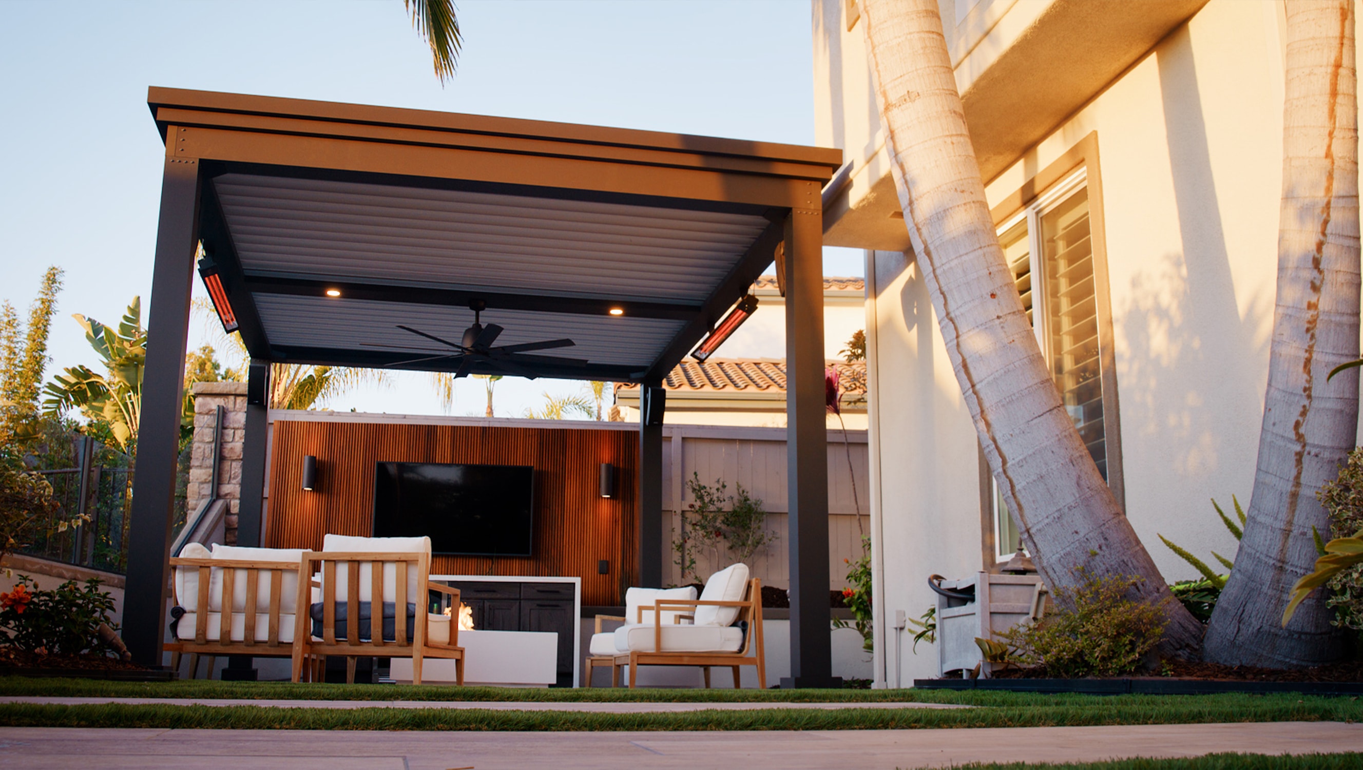 DIY Luxury pergola kit installed over a patio with outdoor furniture and privacy wall with TV.