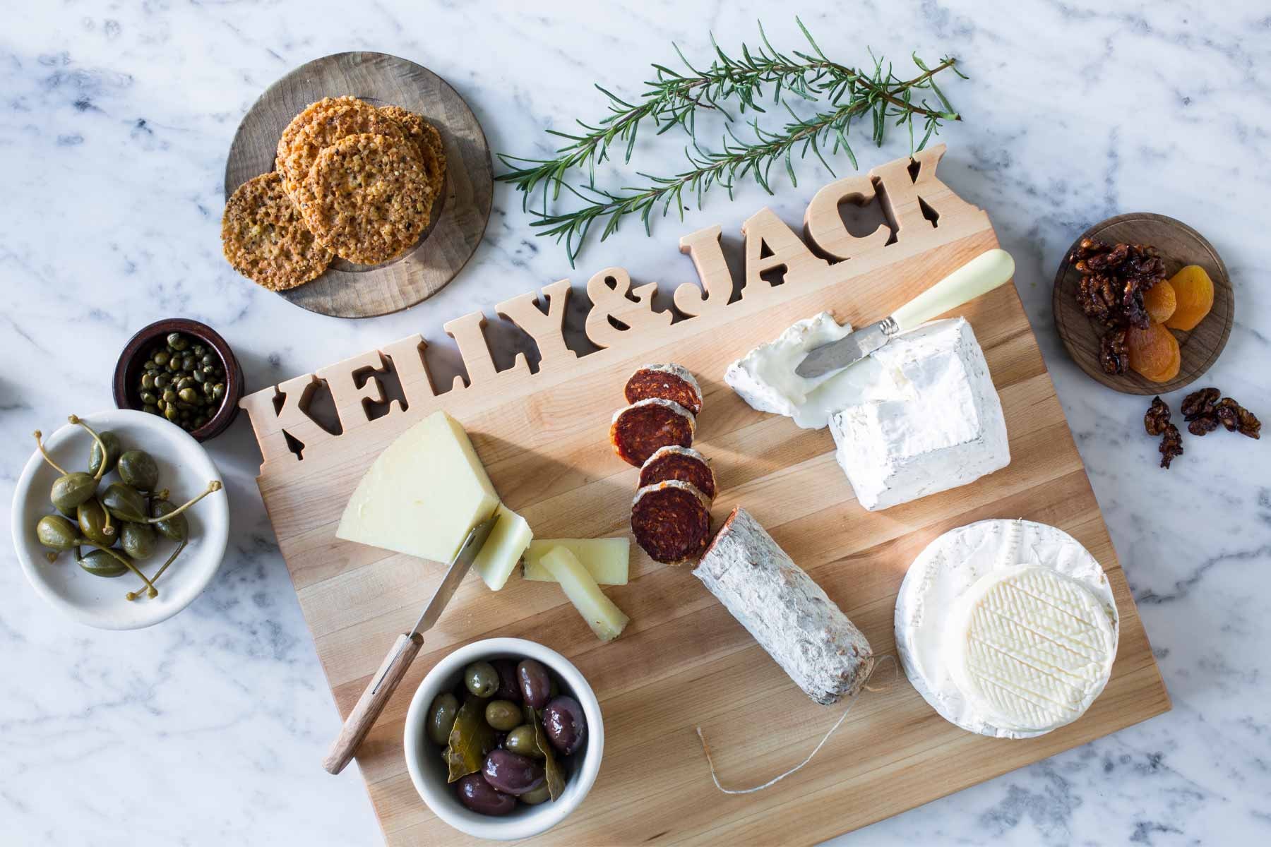 A personalized wooden cutting board featuring two first names is elegantly displayed on a marble kitchen counter, showcasing the perfect blend of style and functionality for home cooks. This essential kitchen utensil adds a unique touch to cooking and entertaining experiences with friends and family.