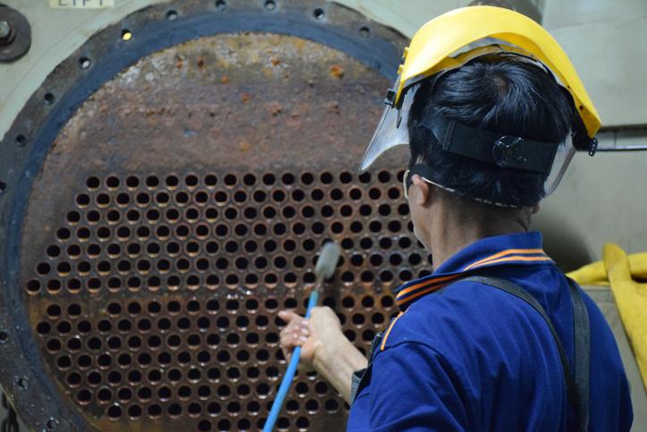 Man fixing a HVAC system, showing how preventive maintenance and asset management are some of the benefits of maintenance software 