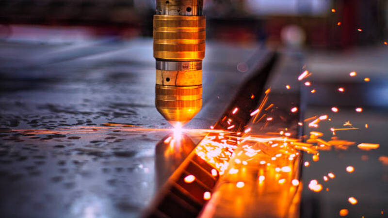 A laser cutter creating a bevel cut on a thick metal sheet. 