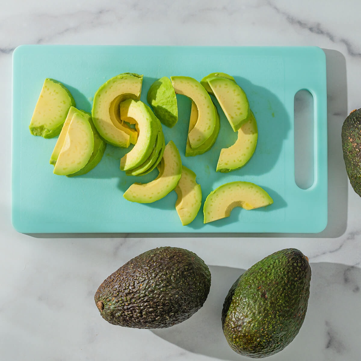 plastic cutting board with cut avocados