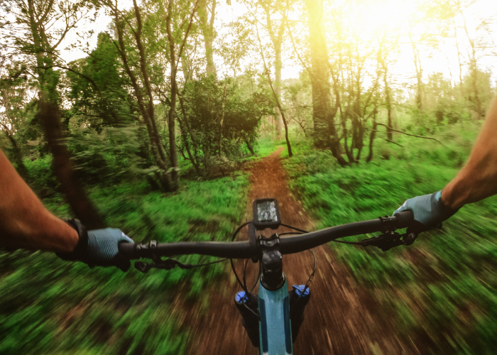 A mountain biker riding a mountain bike on a single track trail with wider tires