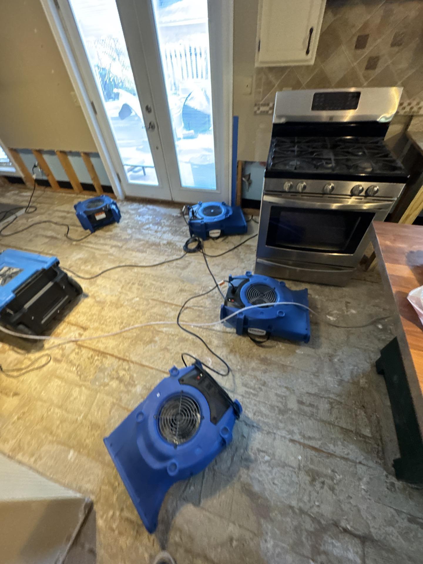 The image shows industrial air movers and dehumidifiers actively drying a room that has experienced flooding, highlighting the flood damage restoration process. These advanced drying equipment tools are essential for preventing mold growth and further structural damage in the affected areas.