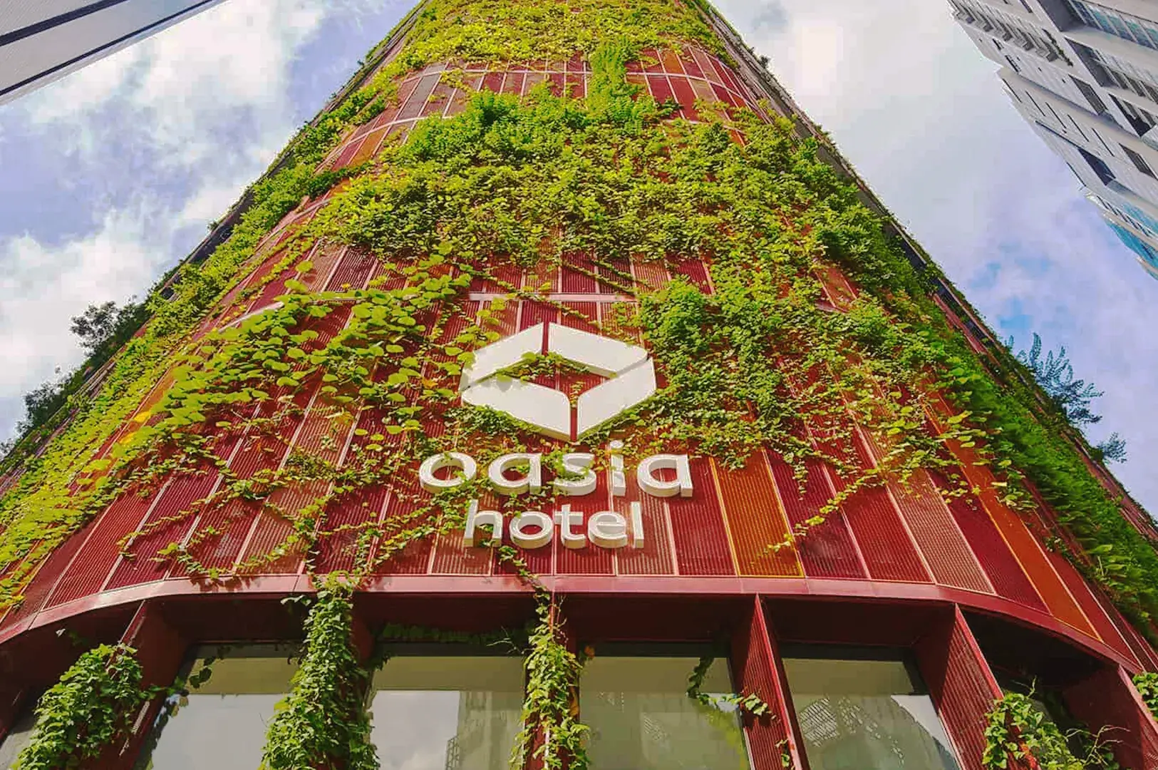Oasia Hotel Singapore vertical garden façade with red panels and lush green climbing plants