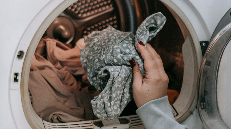 A person is putting viscose clothes into a washing machine