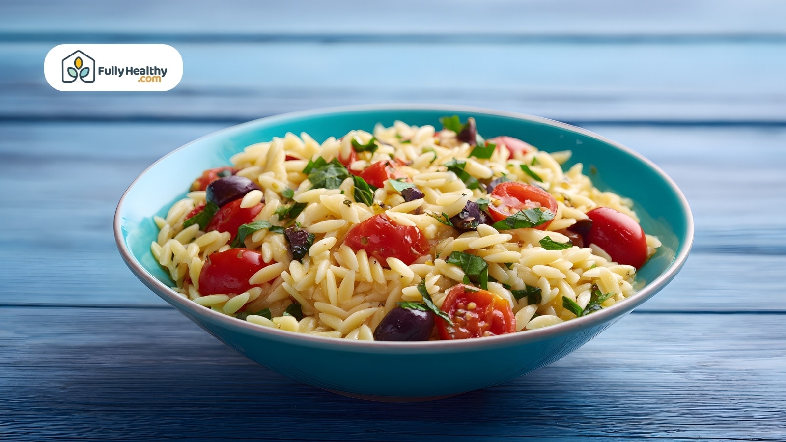 Fresh orzo salad with tomatoes, olives, and herbs in a bowl