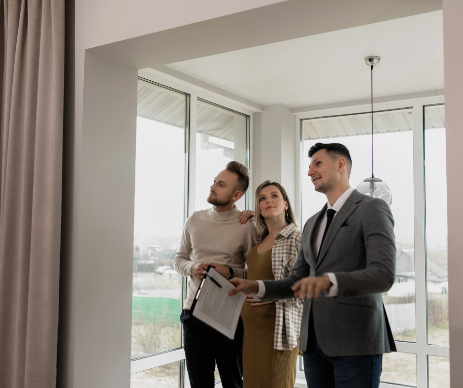 a pregnant woman and her partner in an entryway with a realtor