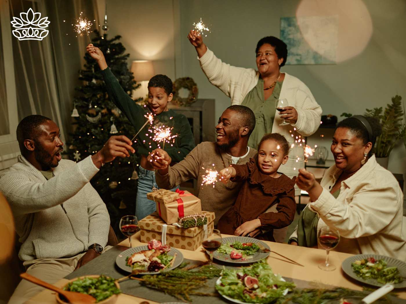Joyful family celebrating Christmas with sparklers around a festive dinner table, part of the Festive Season Collection delivered with heart by Fabulous Flowers and Gifts.
