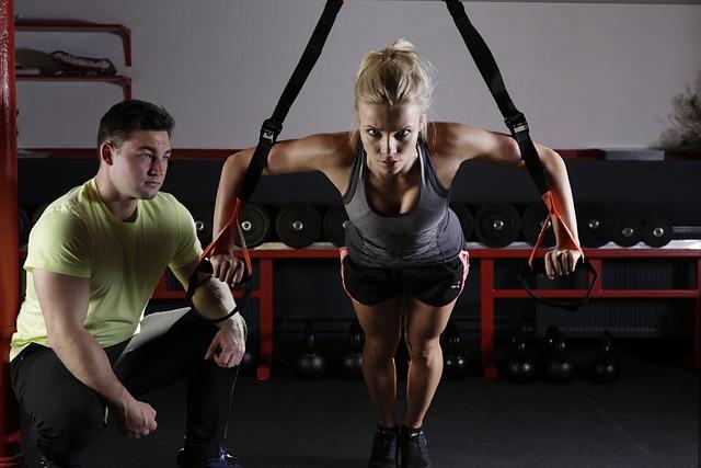 Woman performing resistance training while a coach watches