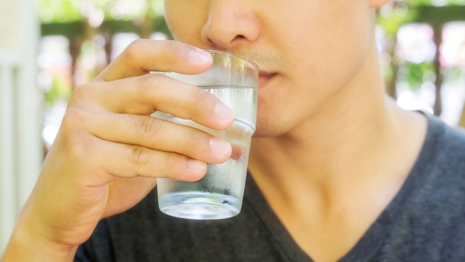 Pria minum air putih dari gelas — menjaga hidrasi membantu proses detoks nikotin