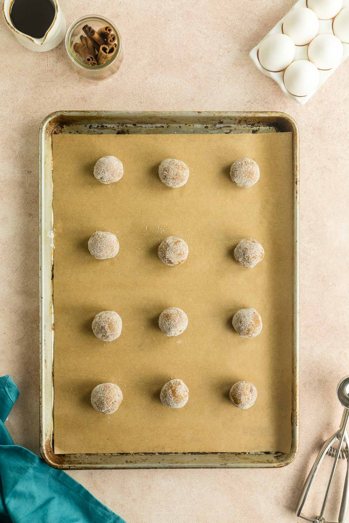 unbaked molasses cookie dough balls rolled in sugar on baking sheet