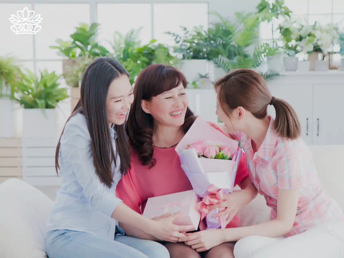Three women sharing a joyful moment, holding a bouquet and gift box. Fabulous Flowers and Gifts.