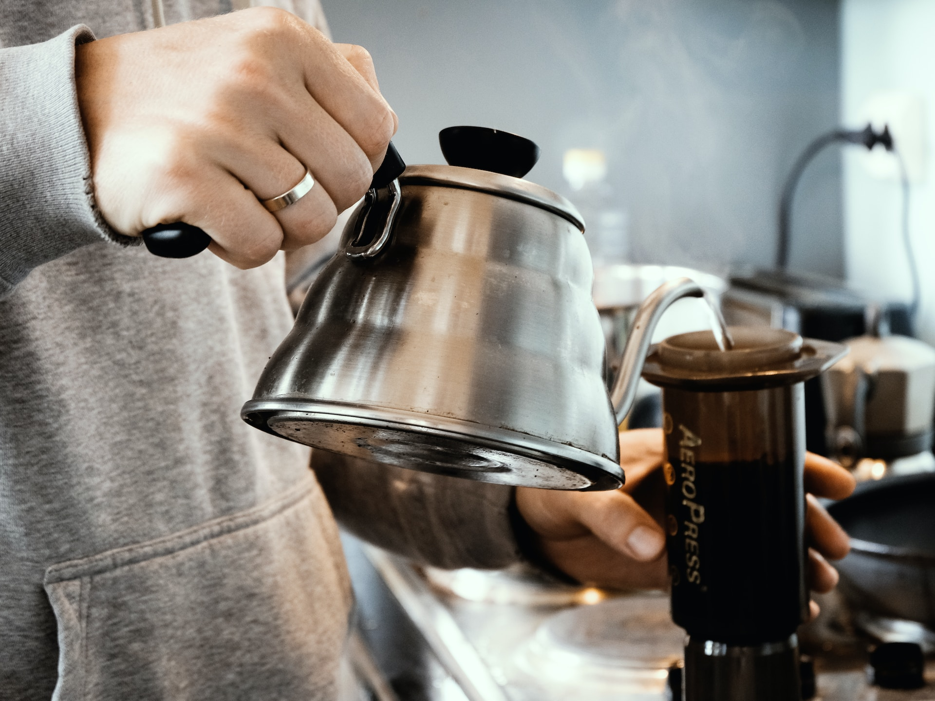 Pouring hot water from a metal pot into an Aeropress brewing device