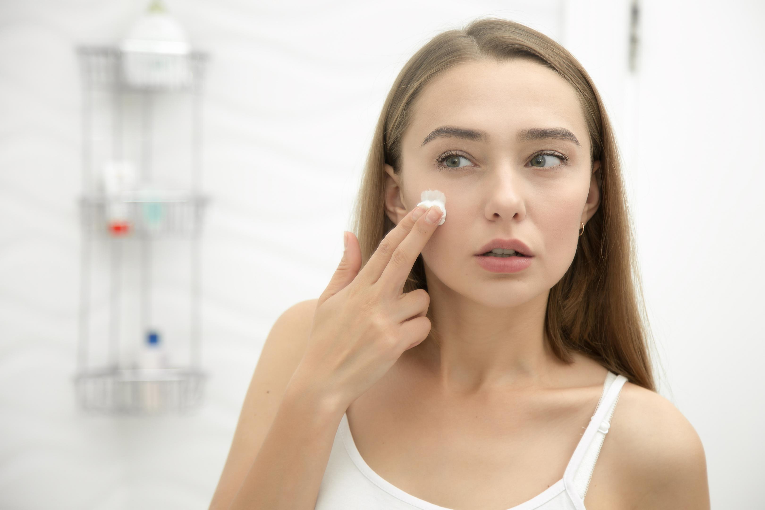 woman applying hair removal cream to her face