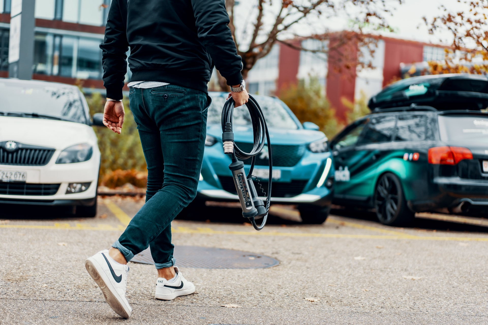 Person walking to their car carrying a Type 2 EV charging cable.