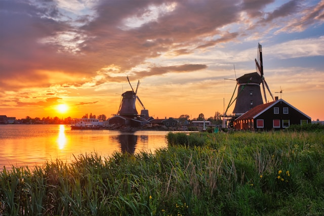 Sun going down behind a lake and windmills in the Netherlands 