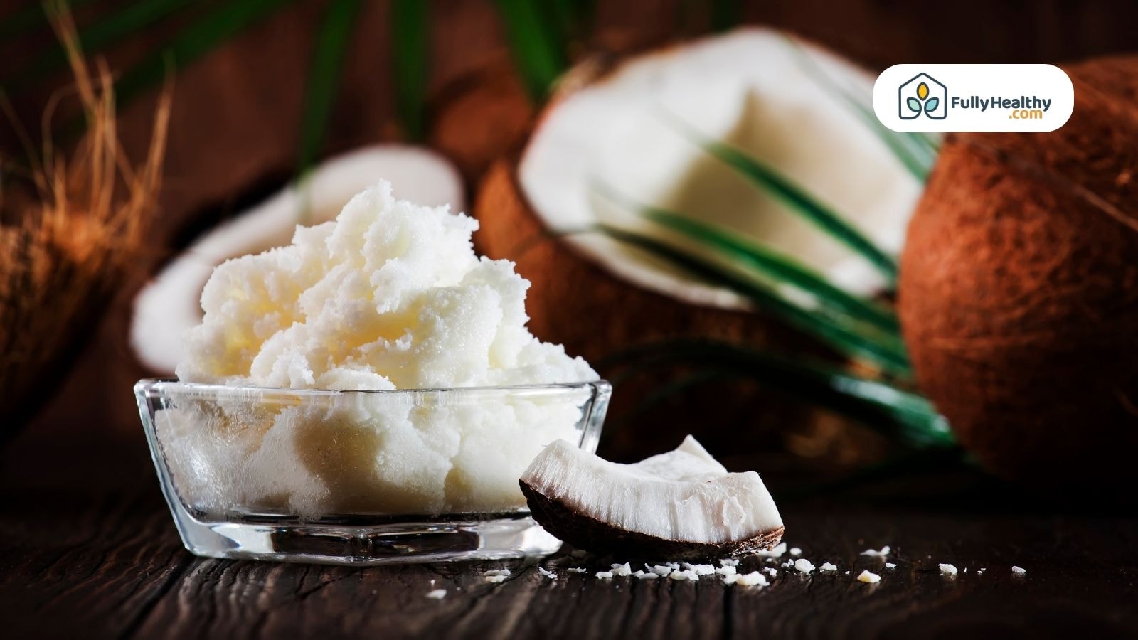 Glass bowl of coconut butter with coconuts behind