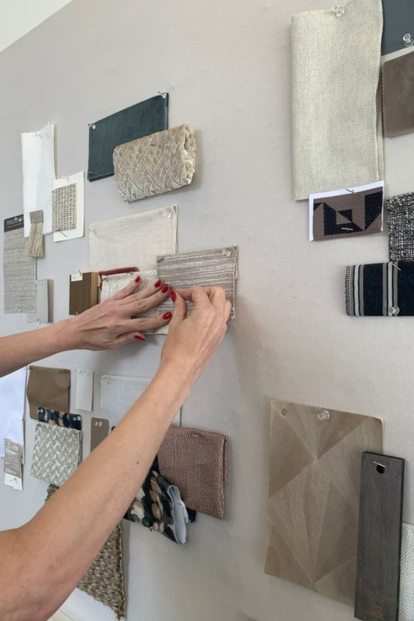 a woman pins wallcoverings and other finishings to a mood board