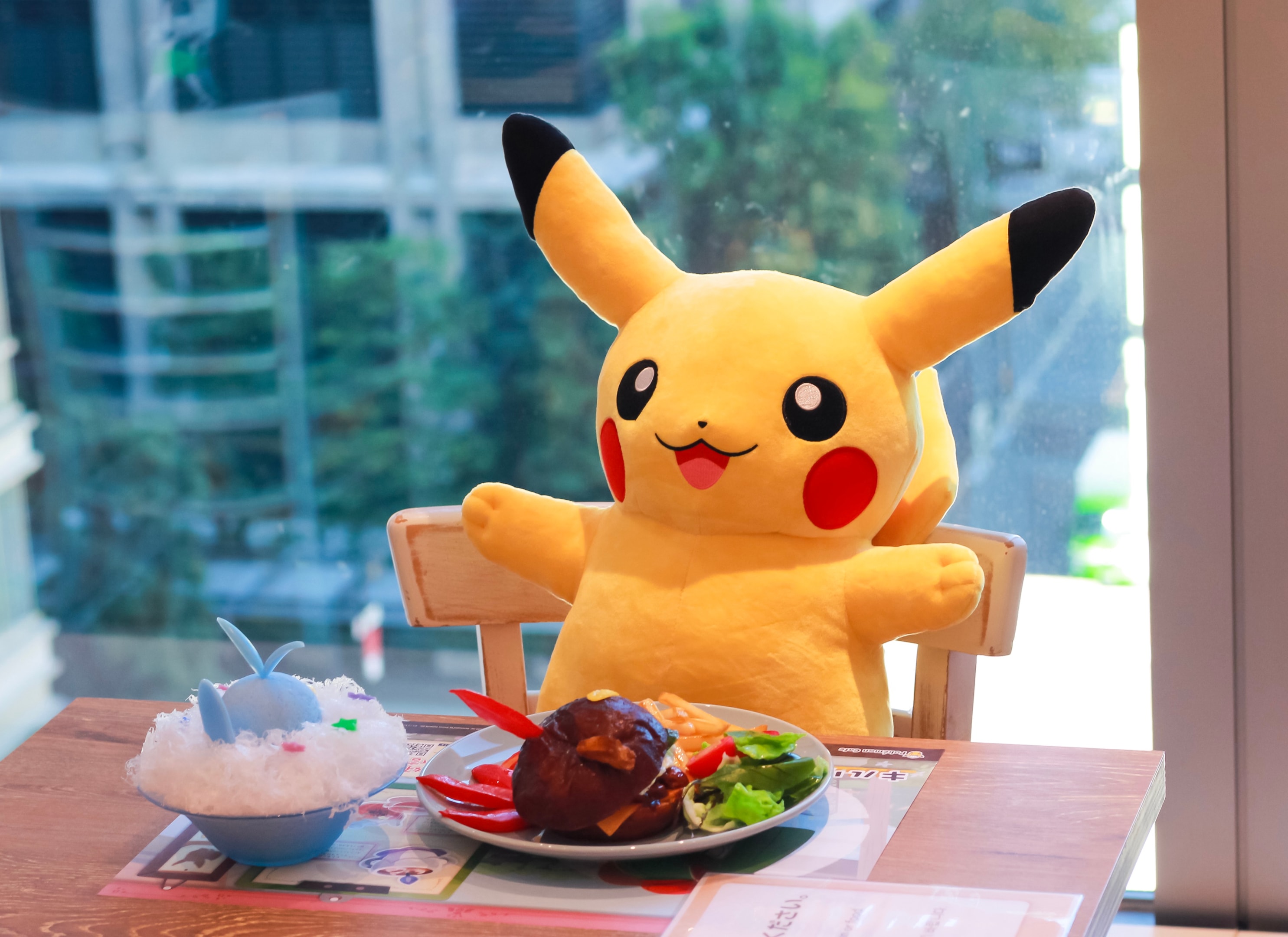 Pokémon Cafe with Pikachu plushie on the seat with food on the table