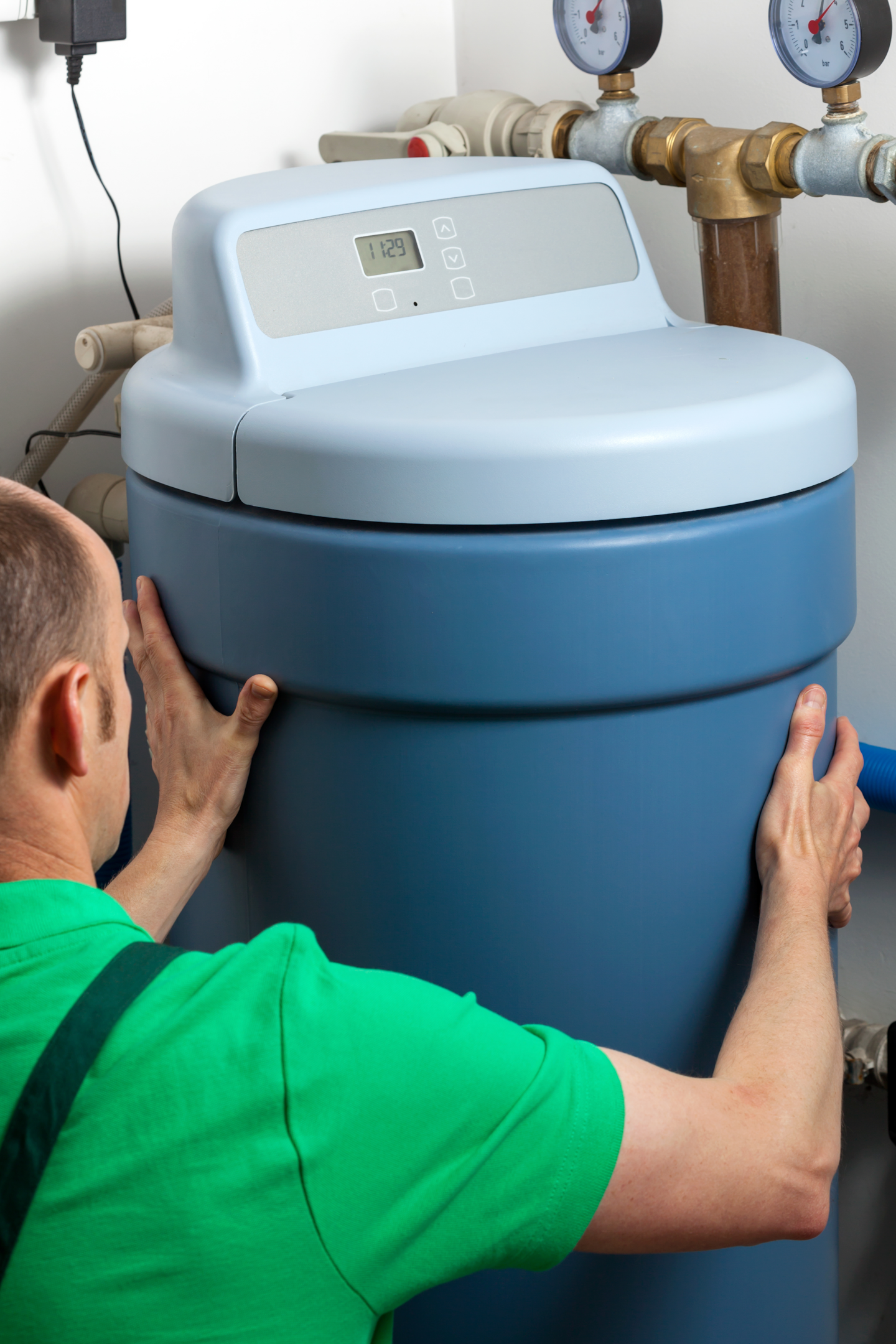 A person installing a water softener system in a home
